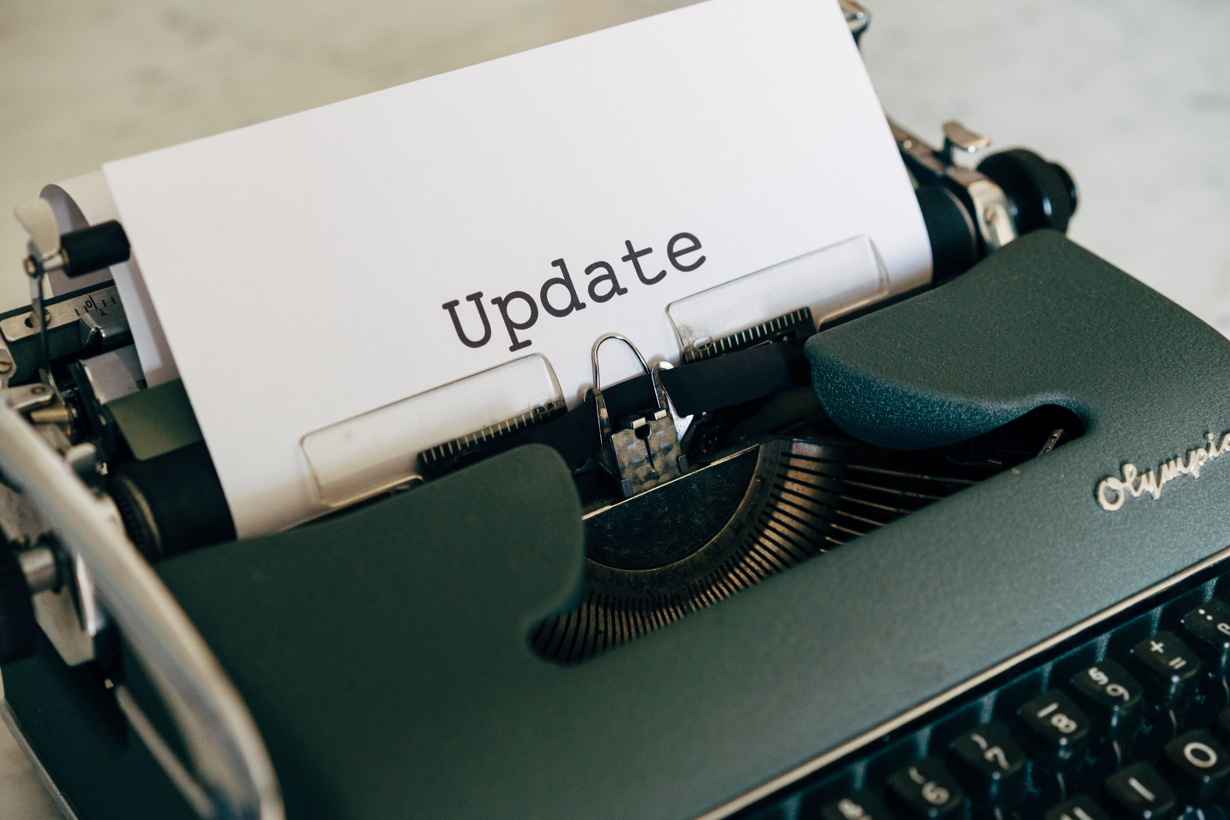 Typewriter with a paper sticking out with a single word: "Update"